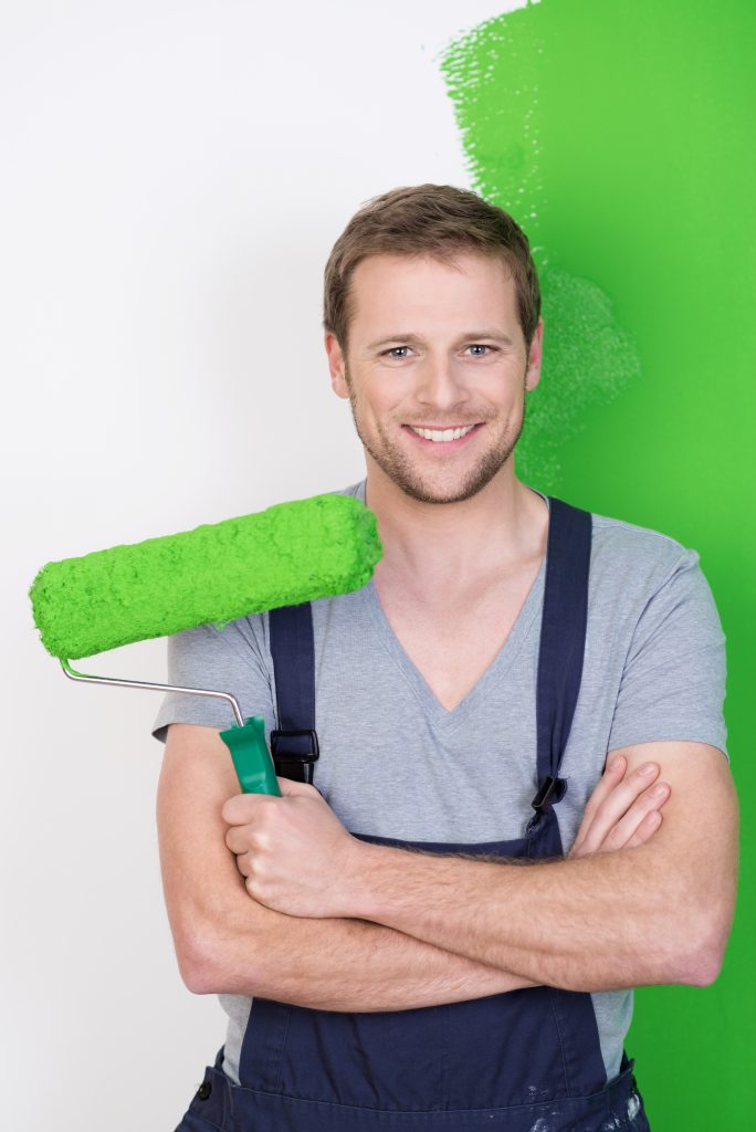painter holding brush preparing for home wall painting service while smiling